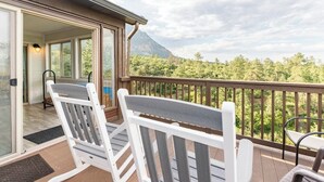 A balcony with two Adirondack chairs, a wooden railing, and a view of a forested mountain range. - 4BR 4BA multi-family with multiple outdoor & indoor living spaces, hot tub, BBQ. (Colorado Springs)
