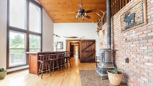 A spacious kitchen with a large island, wooden flooring, and a rustic brick wall with antler decorations. - 4BR 4BA multi-family with multiple outdoor & indoor living spaces, hot tub, BBQ. (Colorado Springs)