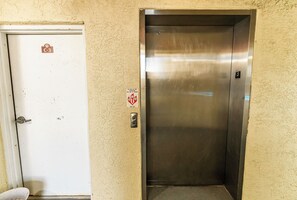 Um elevador com interior metálico e porta branca com etiqueta C-3.