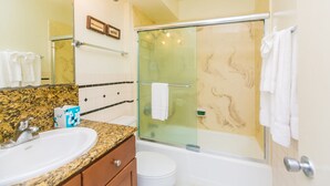 A bathroom with a granite countertop, a white sink, a toilet, and a glass-enclosed shower area. - Charming Ilikai Marina Studio, Great Location In Waikiki! (Honolulu)