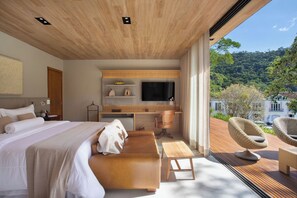 A modern bedroom with a large bed, a desk, and a view of a forested hillside. - Casa Marambaia (Petrópolis)
