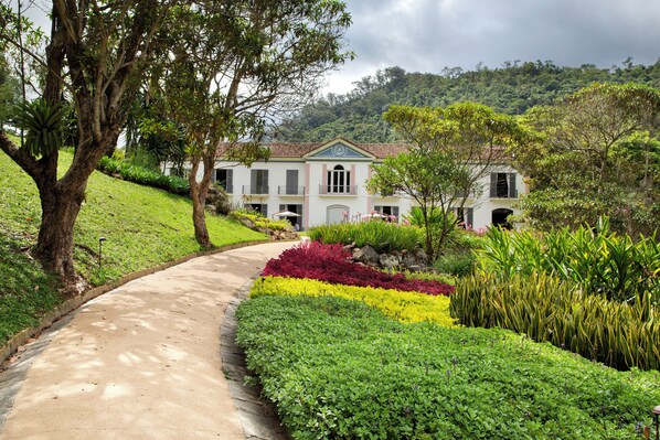 A pathway leading to a house surrounded by lush greenery and a hillside. - Casa Marambaia (Petrópolis)