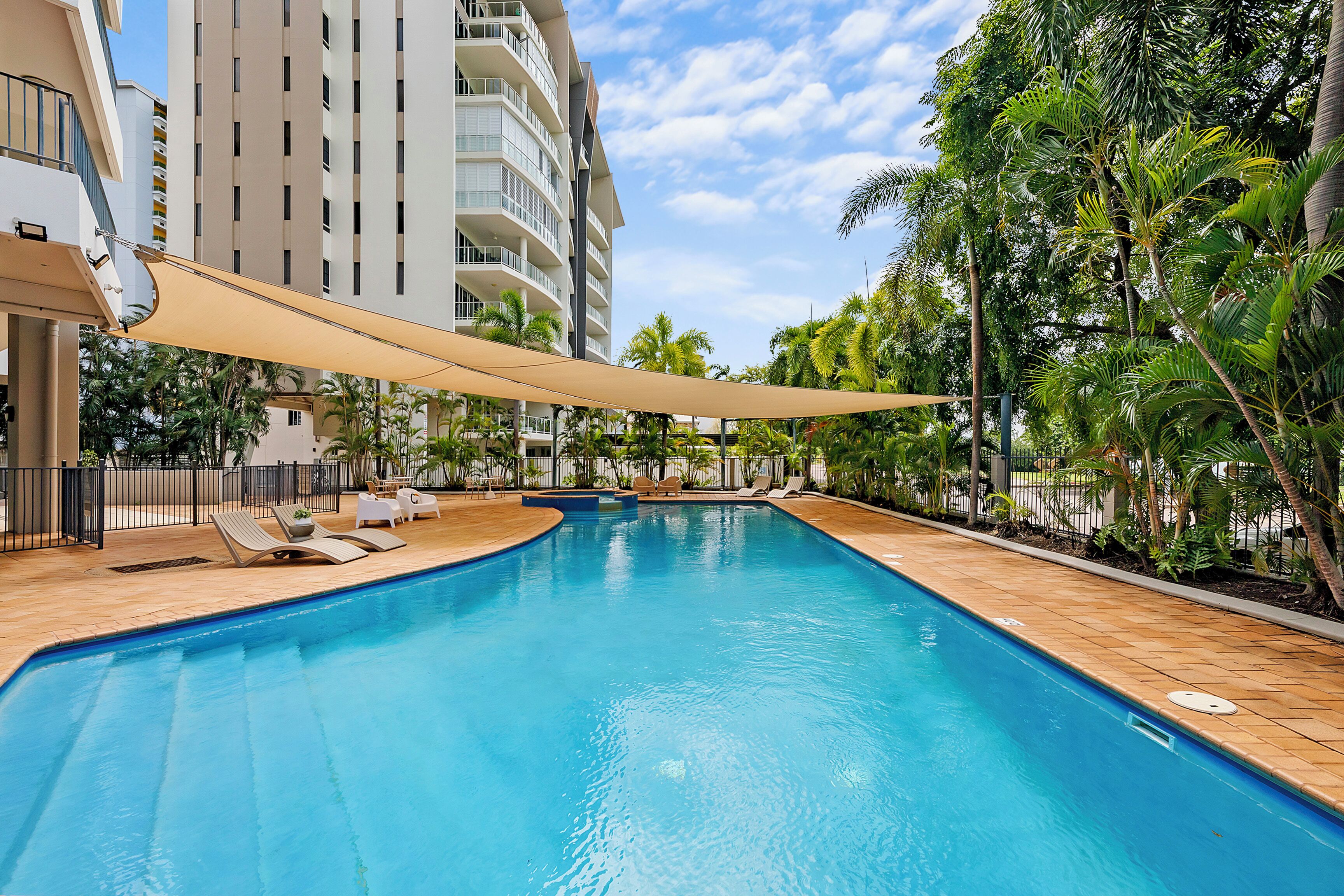 Relax by the shared tropical pool, surrounded by lush greenery and shaded sail canopies—an inviting place to cool off and unwind in Darwin’s warm climate.