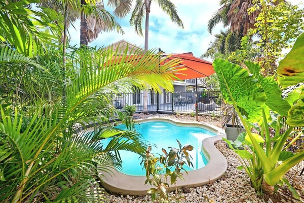 The private pool is surrounded by lush greenery, and sits under a large shade umbrella.