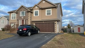 A two-story house with a garage, a driveway, and a parked SUV. - East End Suite (Eastern Passage)
