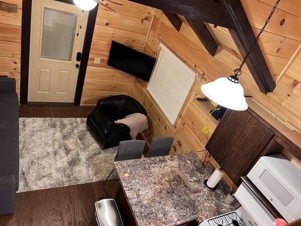 L’intérieur chaleureux d’un chalet, avec un revêtement mural en bois, un fauteuil en cuir noir, un comptoir en granit et un four à micro-ondes.