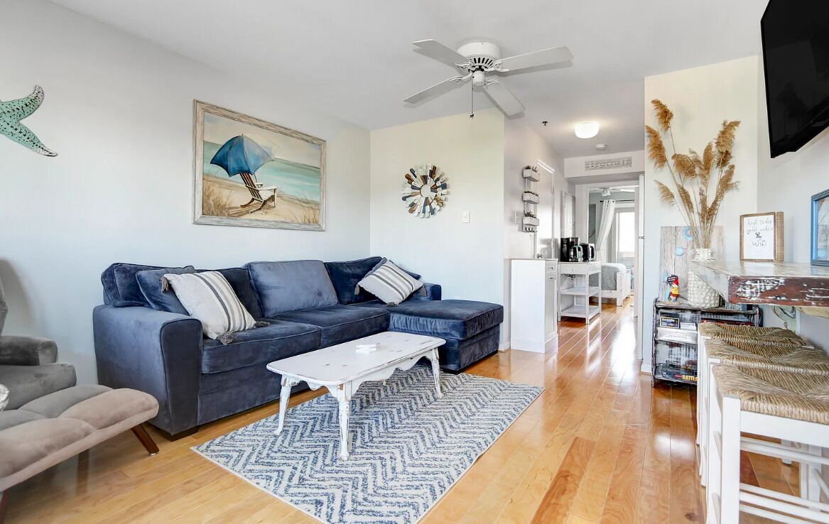 A living room with a blue sofa, a white coffee table, and a patterned rug.