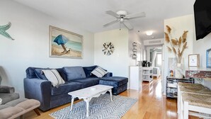 A living room with a blue sofa, a white coffee table, and a patterned rug.