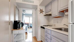 A kitchen with white cabinets, a stove, a sink, and a coffee maker.
