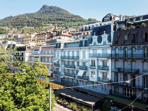 A row of multi-story buildings with balconies, set against a backdrop of a hill. - Le Jazz by Interhome (Montreux)