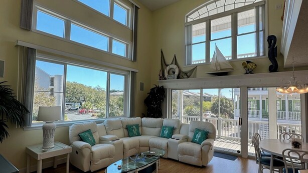 A spacious living room with a large sectional sofa, a glass coffee table, and a dining area with a white table and chairs. - Heart of Ocean Drive just one block to the Beach and Main Street  (North Myrtle Beach)