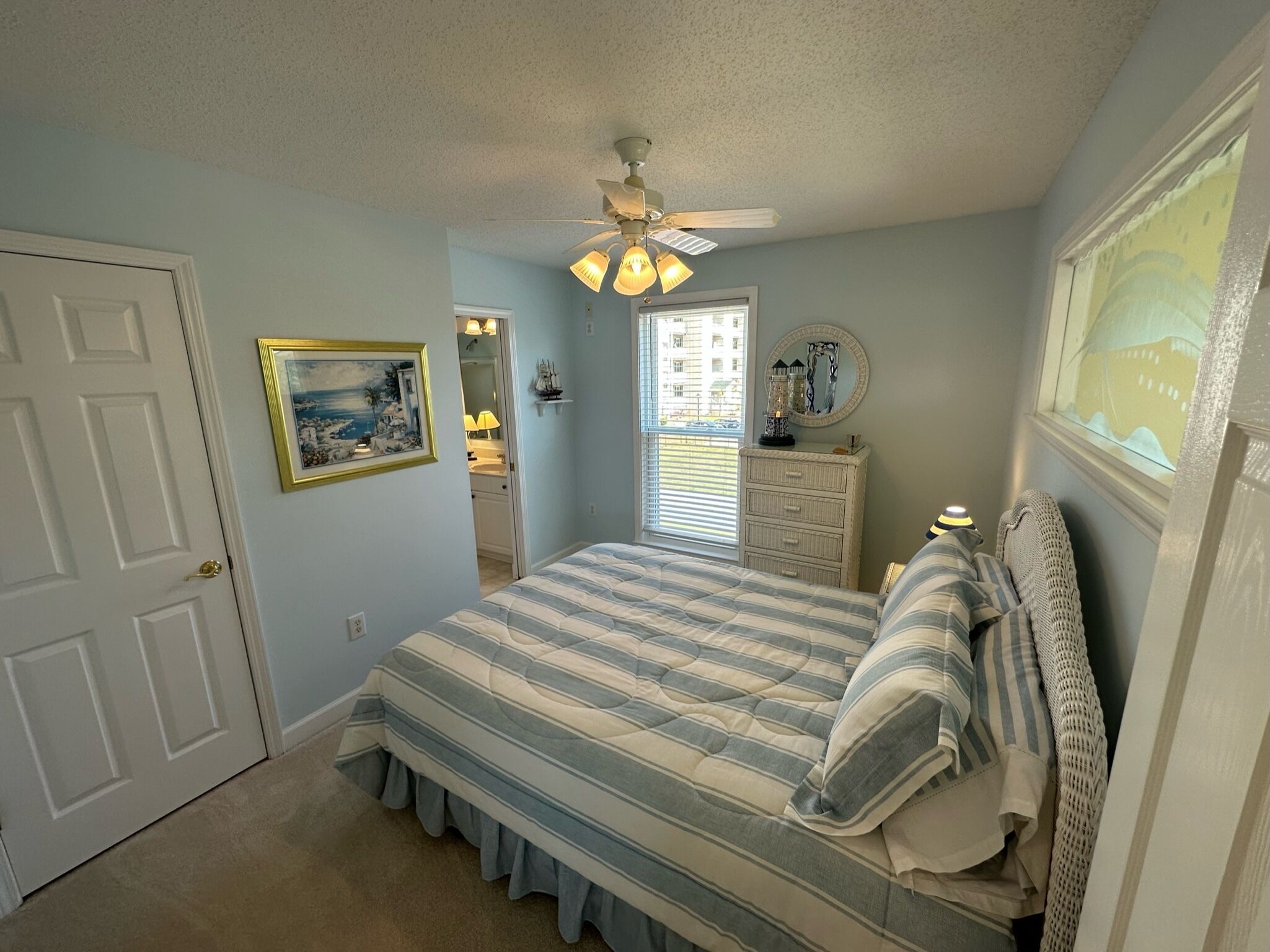 A bedroom with a bed, a dresser, a ceiling fan, and a window.