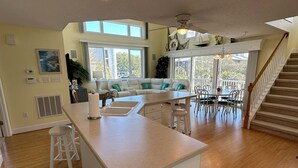A spacious kitchen with a central island, a dining area with a chandelier, and a staircase leading to an upper level. - Heart of Ocean Drive just one block to the Beach and Main Street  (North Myrtle Beach)