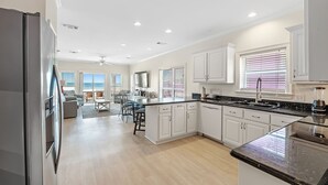 A modern kitchen with white cabinetry, a granite countertop, and a built-in stove. - Holiday Summer Sale! Sundancer E/W. 10BR. Sleeps 36. Beachfront. Pool! PERFECT location. 😎 (Gulf Shores)