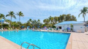 Une piscine à l’eau d’un bleu cristallin, entourée de palmiers et de chaises longues.