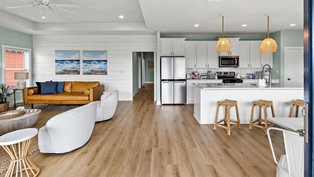 Una cocina moderna con armarios blancos, un refrigerador de acero inoxidable y una isla central con taburetes de bar.