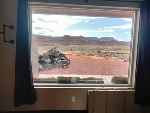 A window with a view of a desert landscape, including rocky formations and distant mountains.