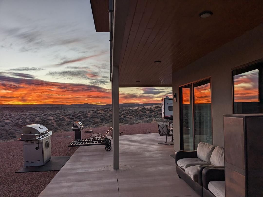 Un patio moderno al aire libre con vistas a una puesta de sol sobre un paisaje desértico.