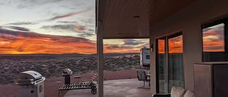 Patio moderno all'aperto con vista su un tramonto nel paesaggio desertico.