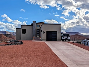 A modern house with a garage, a driveway, and a Jeep parked in front.
