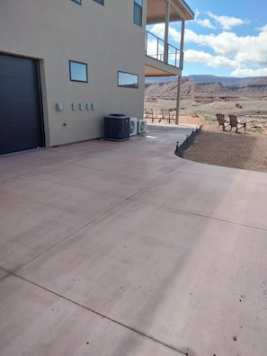 A spacious outdoor patio with a concrete floor, air conditioning units, and a view of a mountainous landscape.