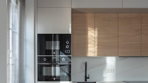 A modern kitchen with a built-in oven, a black faucet, and wooden cabinets. - Meraki Suites (2 Rooms) (Astorga)