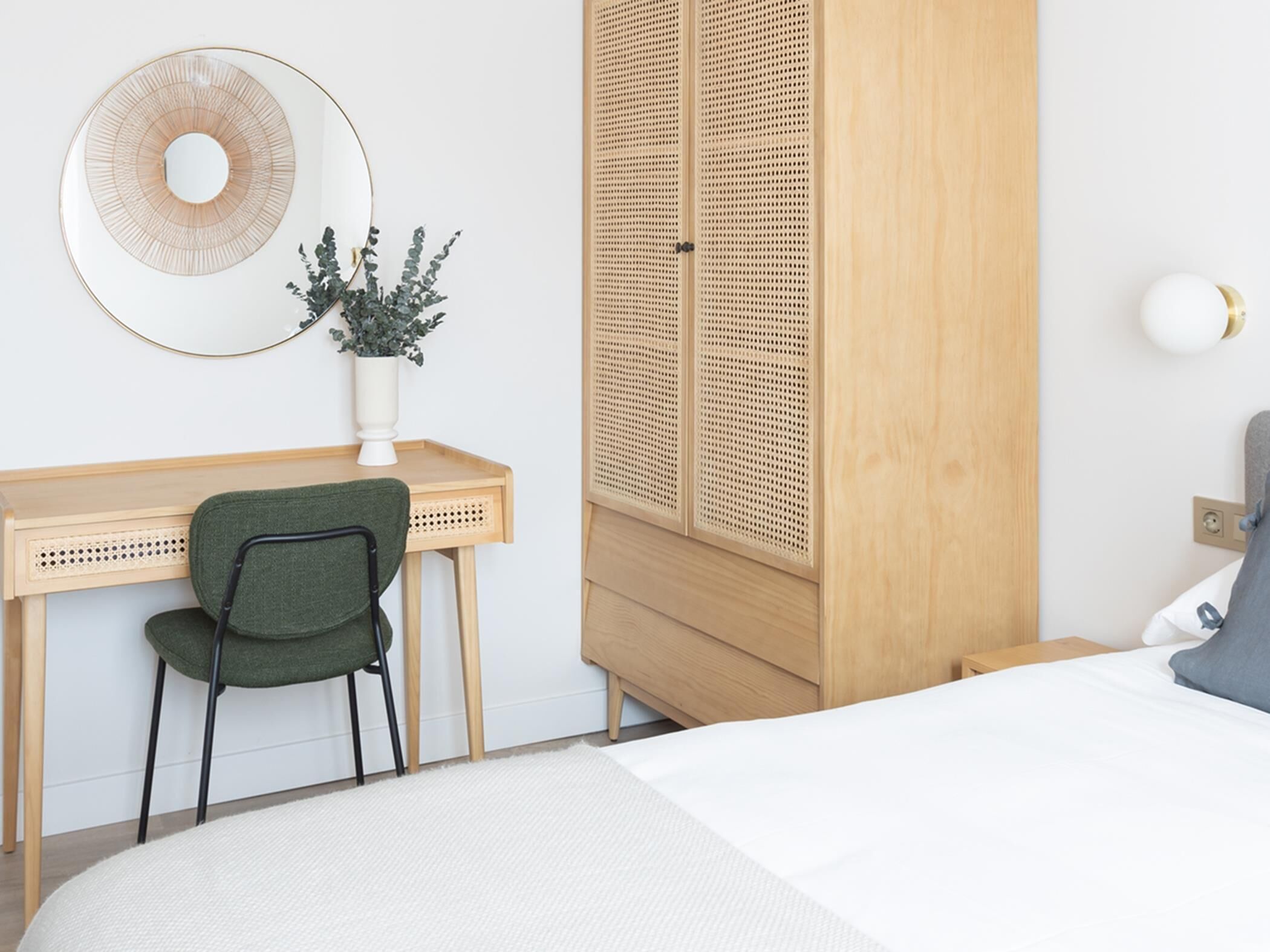 Une chambre à coucher comprenant un lit, un bureau avec une chaise, une armoire et une lampe fixée au mur.