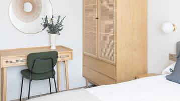 Une chambre à coucher comprenant un lit, un bureau avec une chaise, une armoire et une lampe fixée au mur.