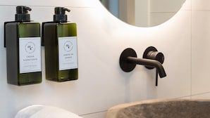 A bathroom with a stone basin, two bottles of body milk, and a towel. - Meraki Suites (2 Rooms) (Astorga)