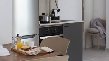 Een moderne keuken met een ingebouwde magnetron, fornuis en spoelbak. Op het aanrecht staat een ontbijtserver met toast en sinaasappelsap.
