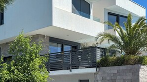 A modern two-story building with large windows, a balcony, and surrounding greenery. - Apartment Oliva by Interhome (Rijeka)