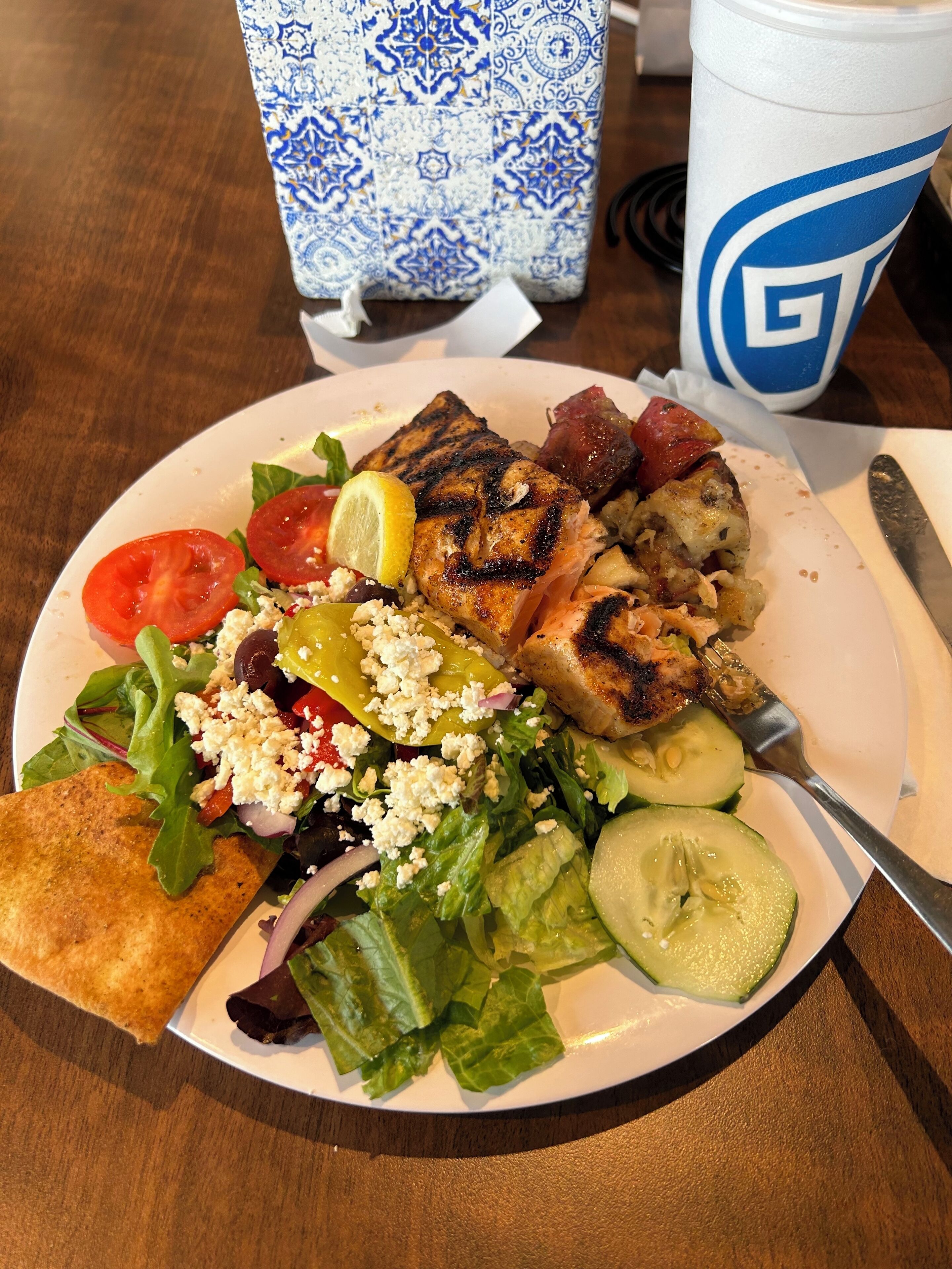 A plate of food with grilled chicken, salad, and a side of potatoes.