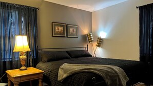 Un dormitorio ordenado con cama, mesita de noche, lámpara y dos lámparas de pared.