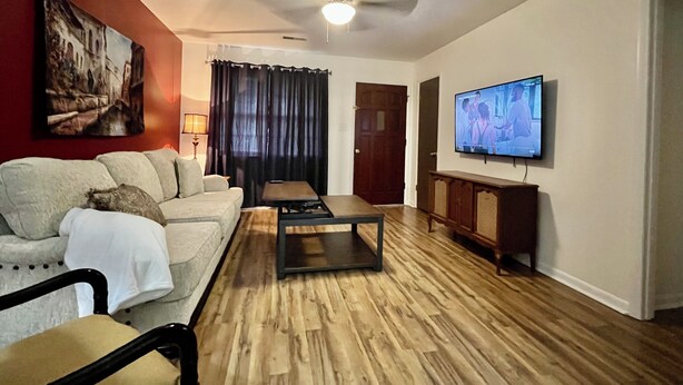 Una sala de estar con sofá, mesa de centro, televisor y un cuadro en la pared.