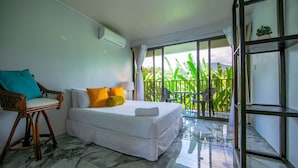 Una camera d'albergo con un letto, una sedia e un balcone vista verde.