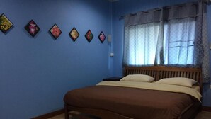 Une chambre à coucher avec un lit en bois, des murs bleus et une fenêtre ornée de rideaux à motifs.