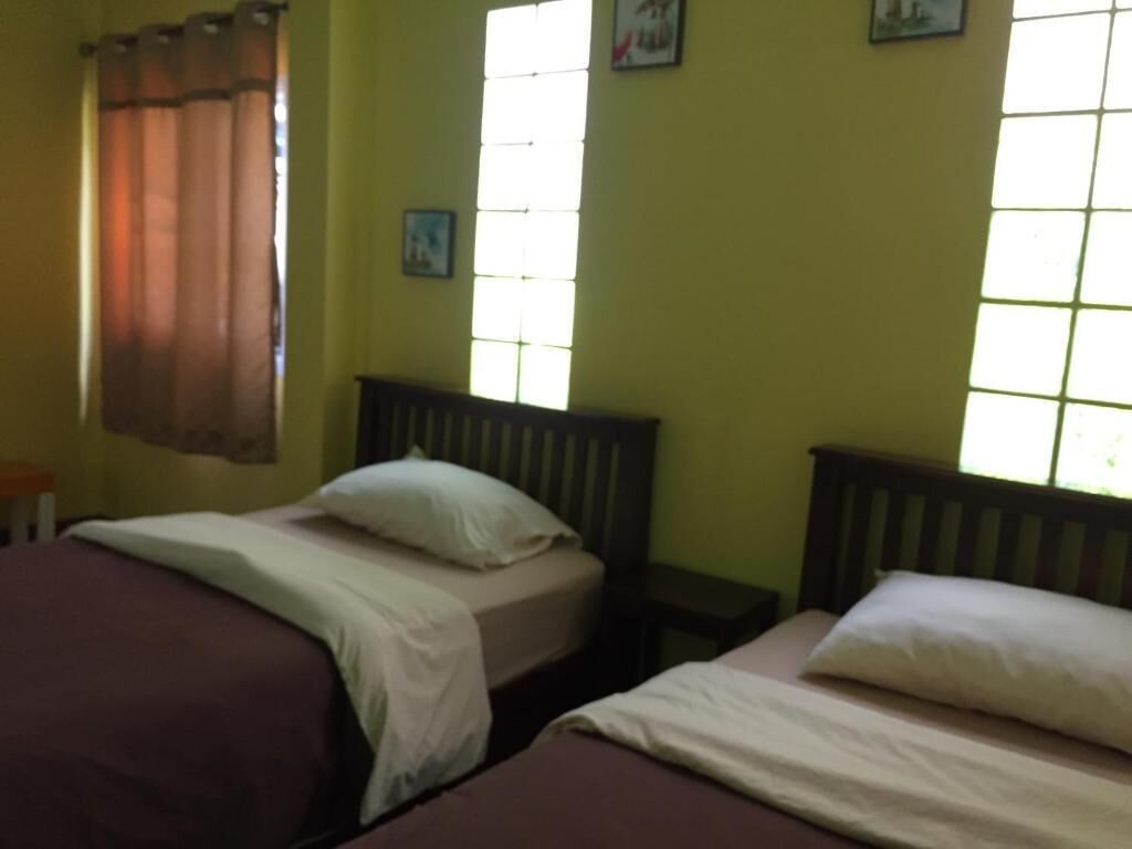 Une chambre avec deux lits, une fenêtre avec des rideaux et une petite table.