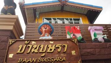 A wooden sign with Thai text and a logo, indicating a location named "BAAN BUSSARA".