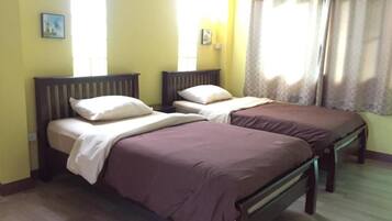 Una habitación con dos camas, cabeceros de madera y una ventana con cortinas.