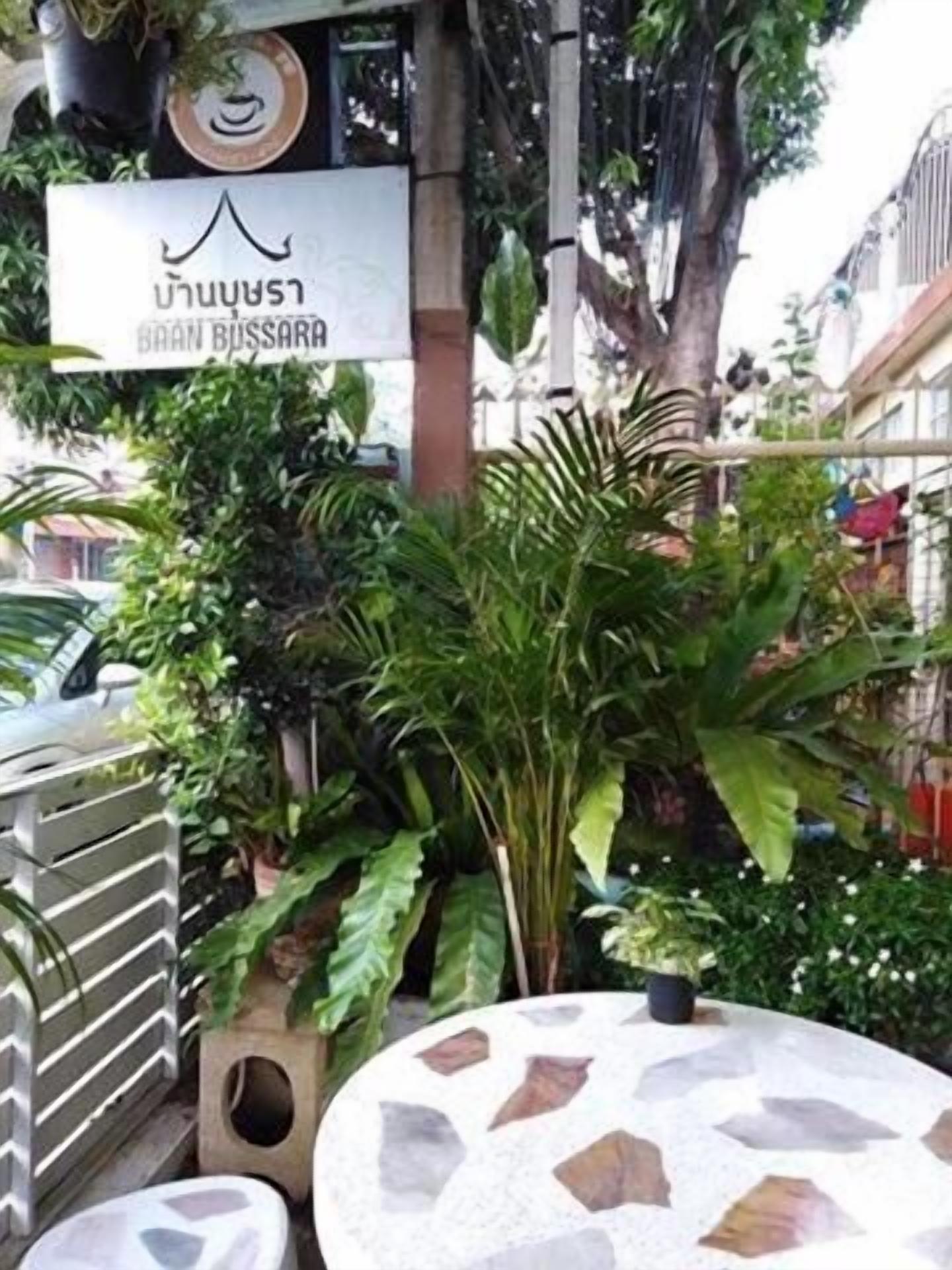 A restaurant with outdoor seating, surrounded by lush greenery and a sign reading "BRAN BUSSARA".