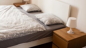 A neatly made bed with patterned bedding, a bedside table with a lamp, and a nightstand with a drawer. - 2 Bed Flat - Sleeps 9 - Pets - Smoking on terrace (Praha)