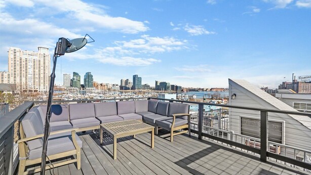 A rooftop deck with a sofa set, a table, and a lamp. - Charming Baltimore Townhome w/ Scenic Views (Baltimore)