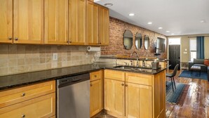 A modern kitchen with wooden cabinets, a brick backsplash, and a central island with a sink. - Charming Baltimore Townhome w/ Scenic Views (Baltimore)