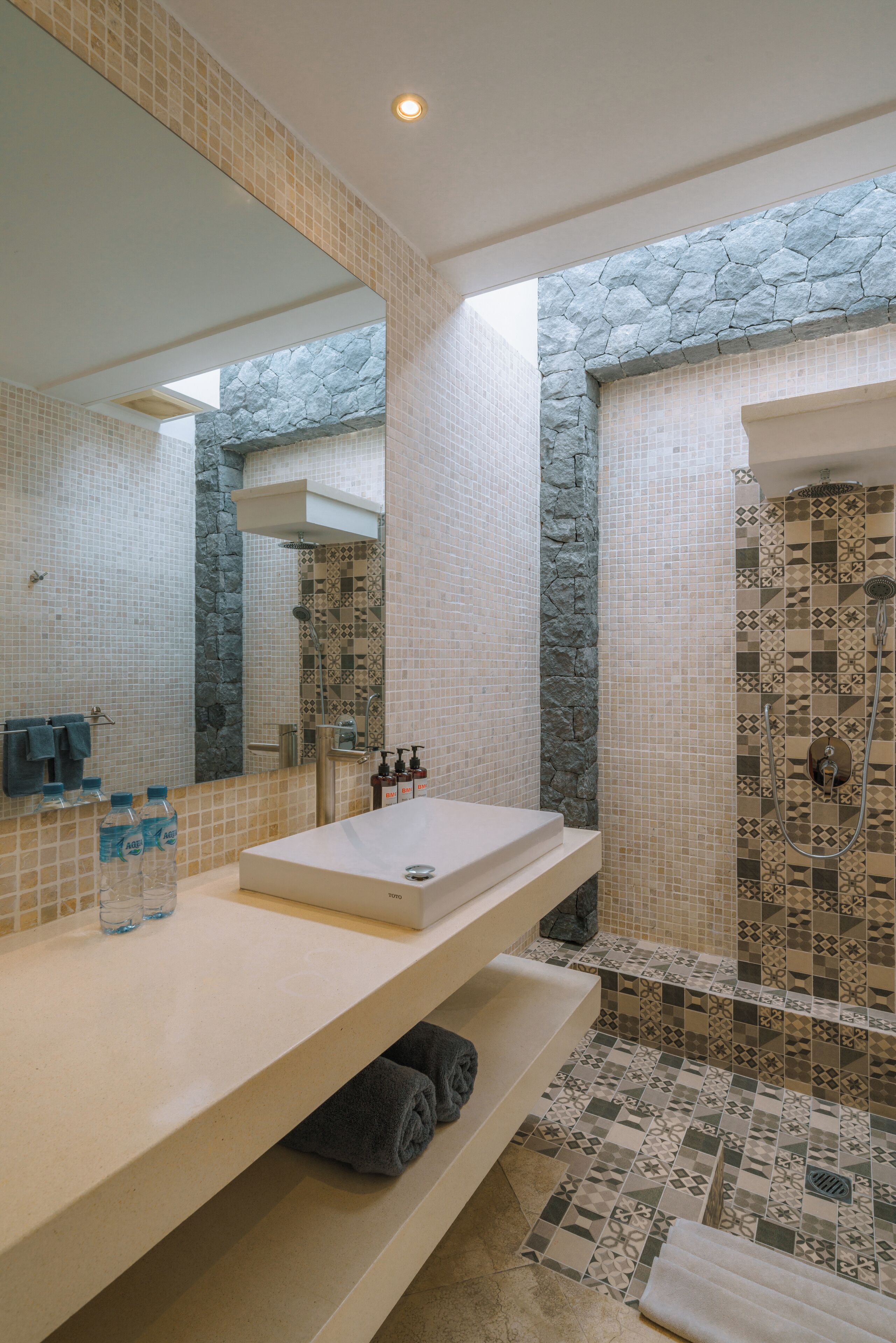 Une salle de bain avec un grand miroir, un lavabo et un espace douche.