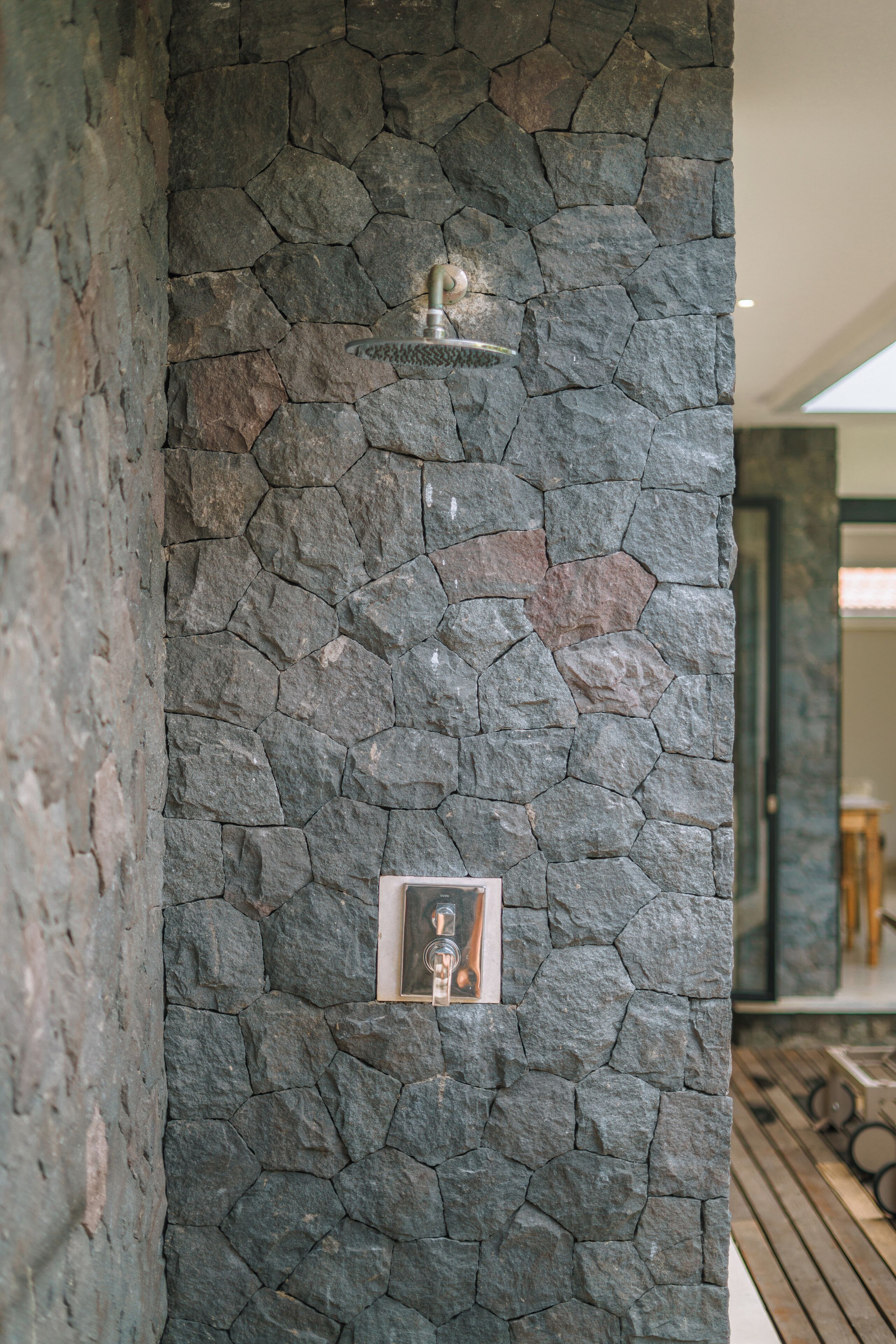 A stone wall with a showerhead and a framed picture.