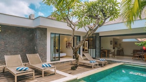 A modern outdoor pool area with lounge chairs and a tree. - Villa Anahata (Seminyak)