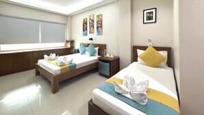 A hotel room with two beds, a skylight, artwork on the walls, and a window with blinds. - Sunburn Suites Coron (Coron)