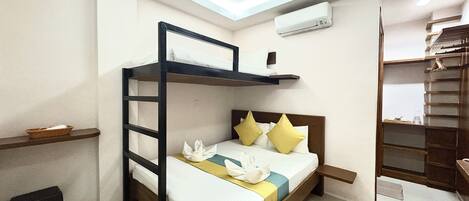 A bunk bed room with a desk, a small stool, and a built-in wardrobe.
