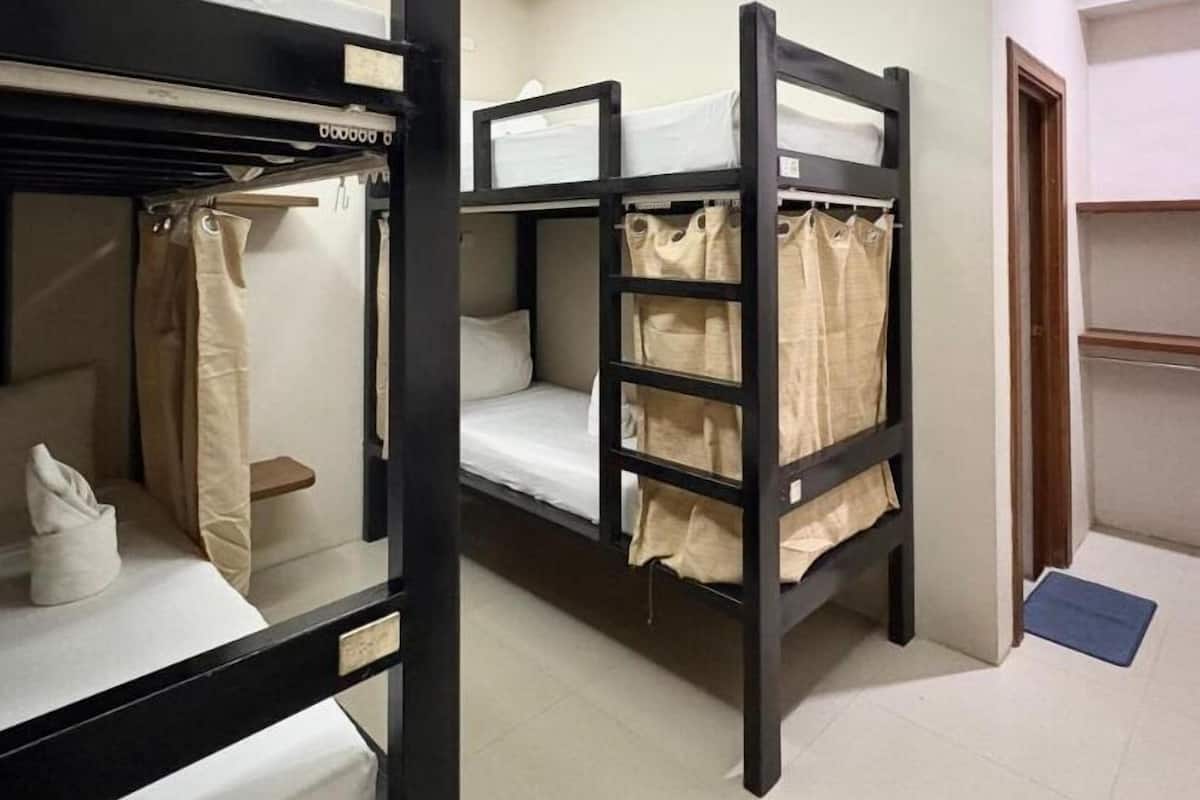 Un dormitorio con literas, una cortina de ducha y un estante pequeño.