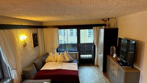 A hotel room with a bed, a sofa, a TV, and a desk. - Apartment 'Andys Bergglück' with Mountain View, Balcony and Wi-Fi (Leutasch)